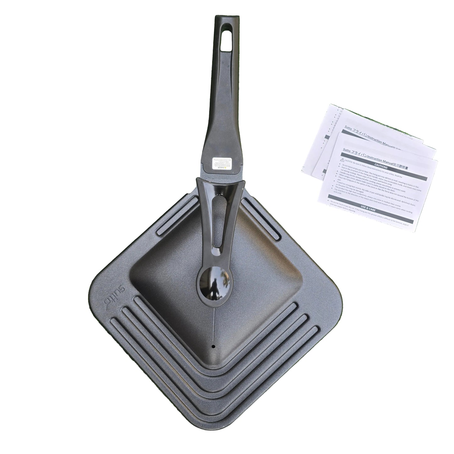 Gray portable grill and spatula set on green grass with user manual.